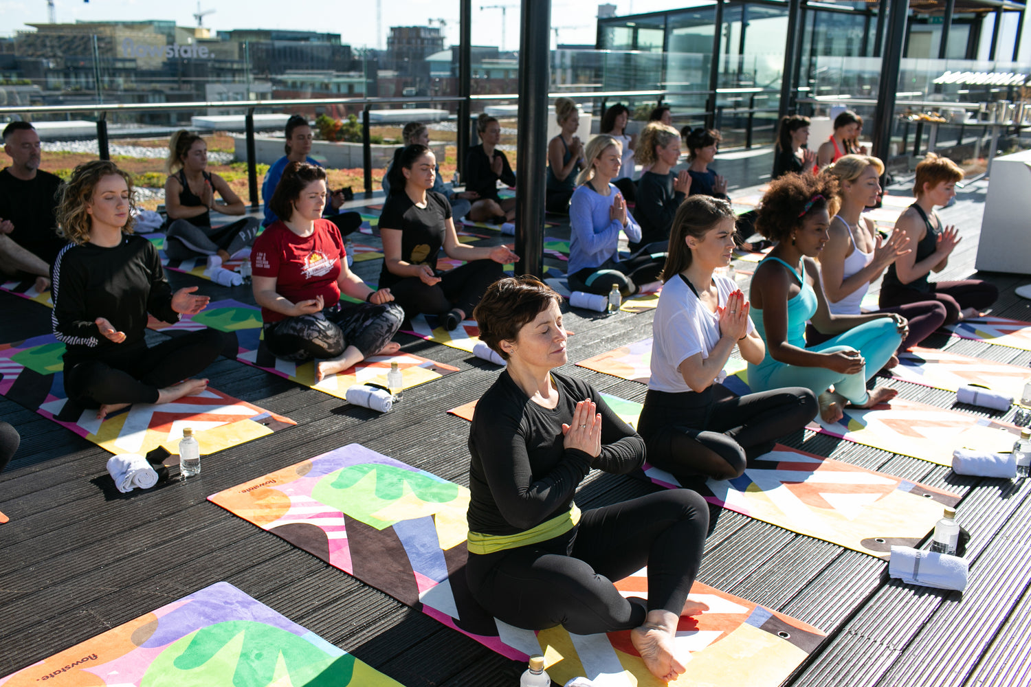 A large group of people practicing yoga on Flowstate yoga mats in the sun