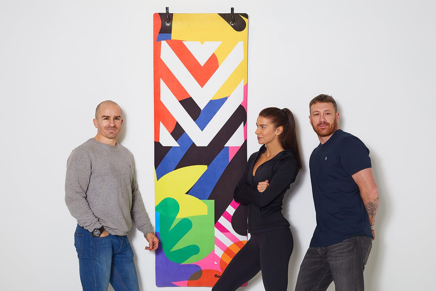 Adrienne, John and Maser from Flowstate standing in front of a hanging yoga mat