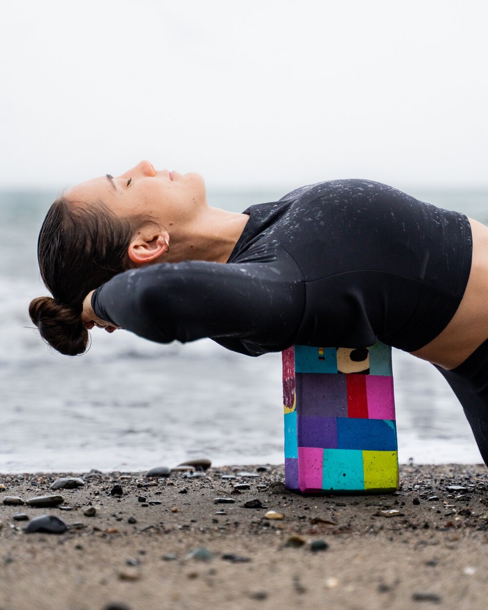Someone practicing yoga on the Flowstate x Oceansole Yoga Block on a beach